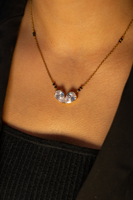 Close-up of a woman wearing the gold Advita Mangalsutra, featuring a delicate chain with black beads and a pendant of two pear-cut stones angled together.