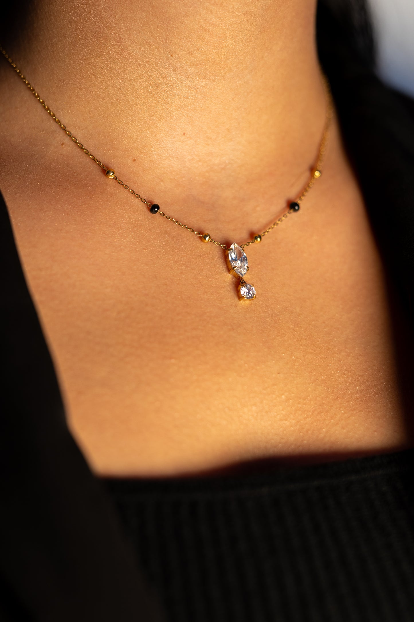 Ekya Mangalsutra with a delicate gold chain, black beads, and a teardrop pendant.