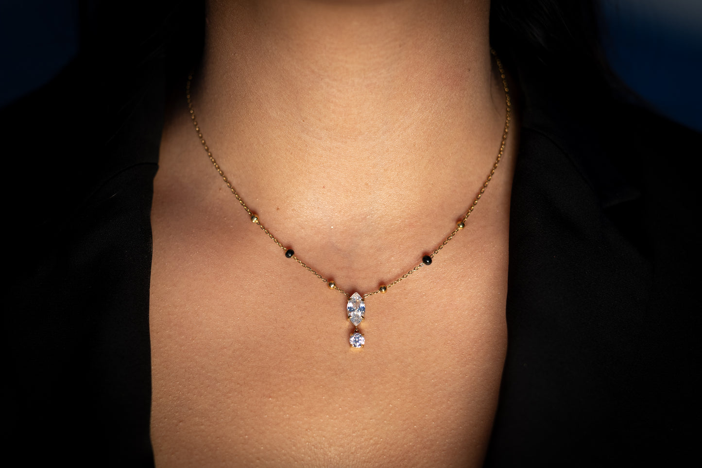 Close-up of a woman wearing the Ekya Mangalsutra, featuring a delicate gold chain with spaced black beads and a sparkling teardrop and round stone pendant.