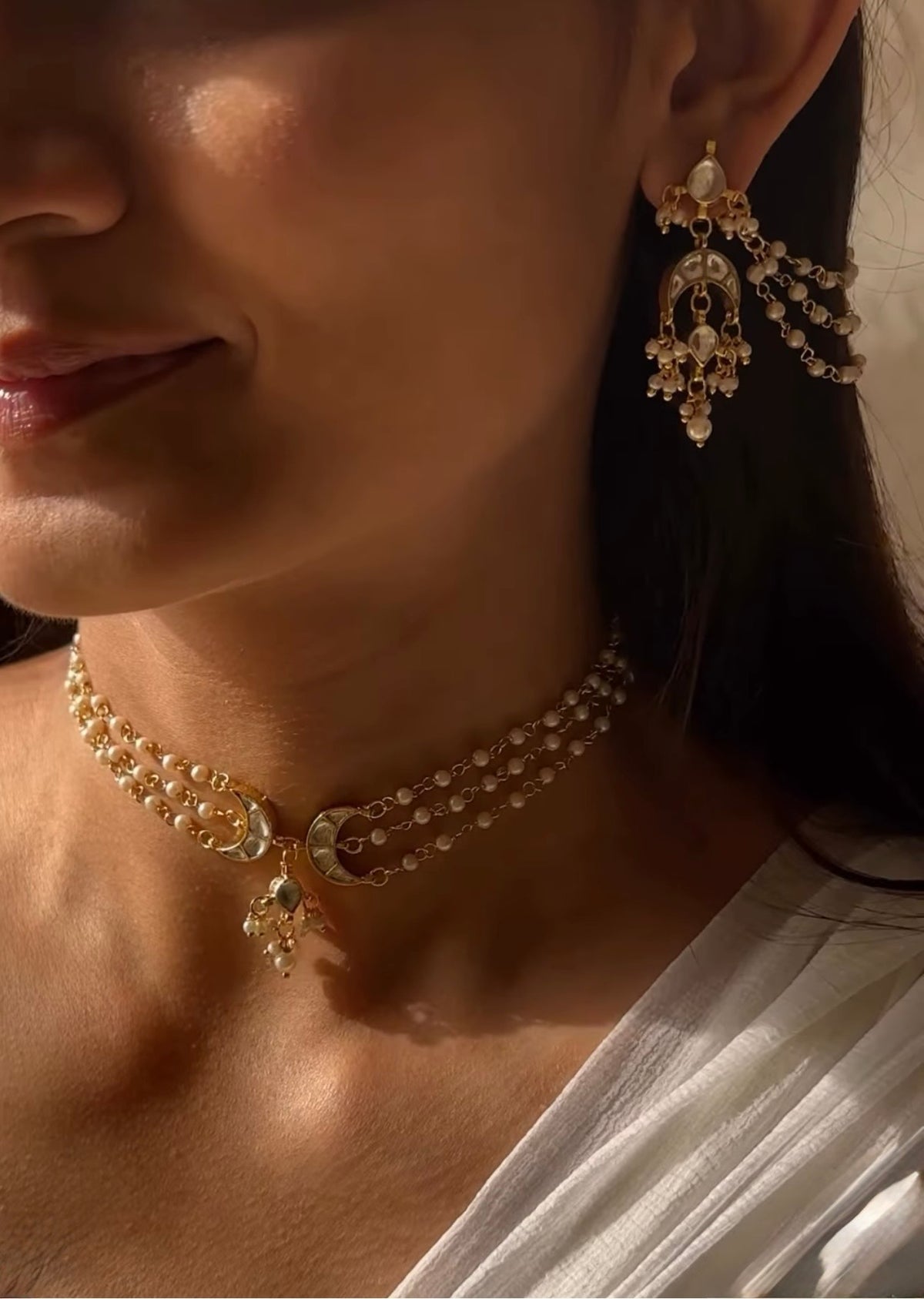 Model wearing the Liyana Set by Kirasa London, featuring a triple-strand pearl Kundan choker and matching chaandbali earrings with pearl sahare ear chains.