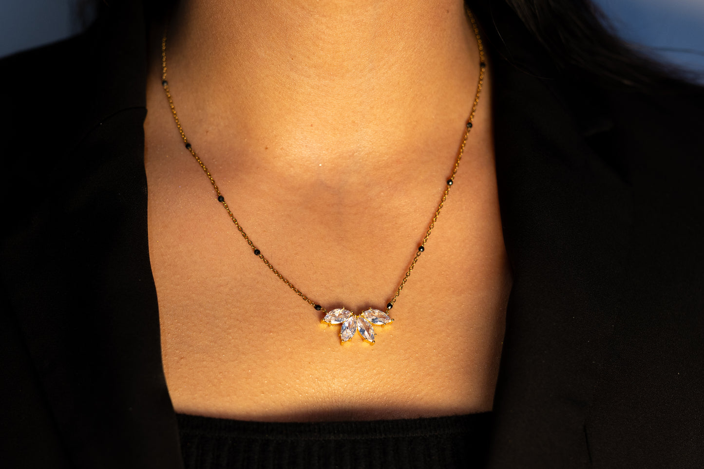 Close-up of a woman wearing the gold Padma Mangalsutra, featuring a delicate chain with black beads and a sparkling lotus flower pendant made of clear marquise stones.