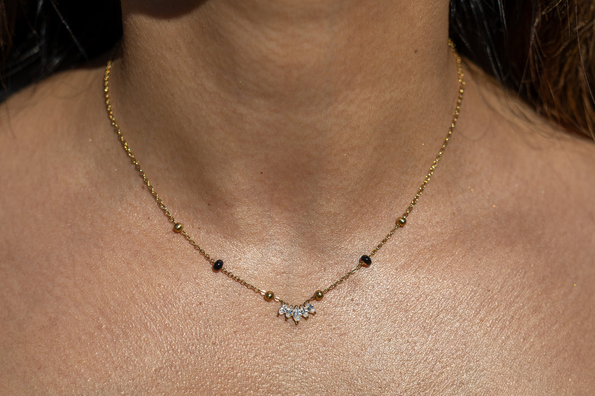 Close-up of a model wearing the Kirosa London gold Padma 2.0 Mangalsutra Necklace, featuring a lotus-inspired curved cluster pendant of marquise crystals flanked by signature black and gold beads.
