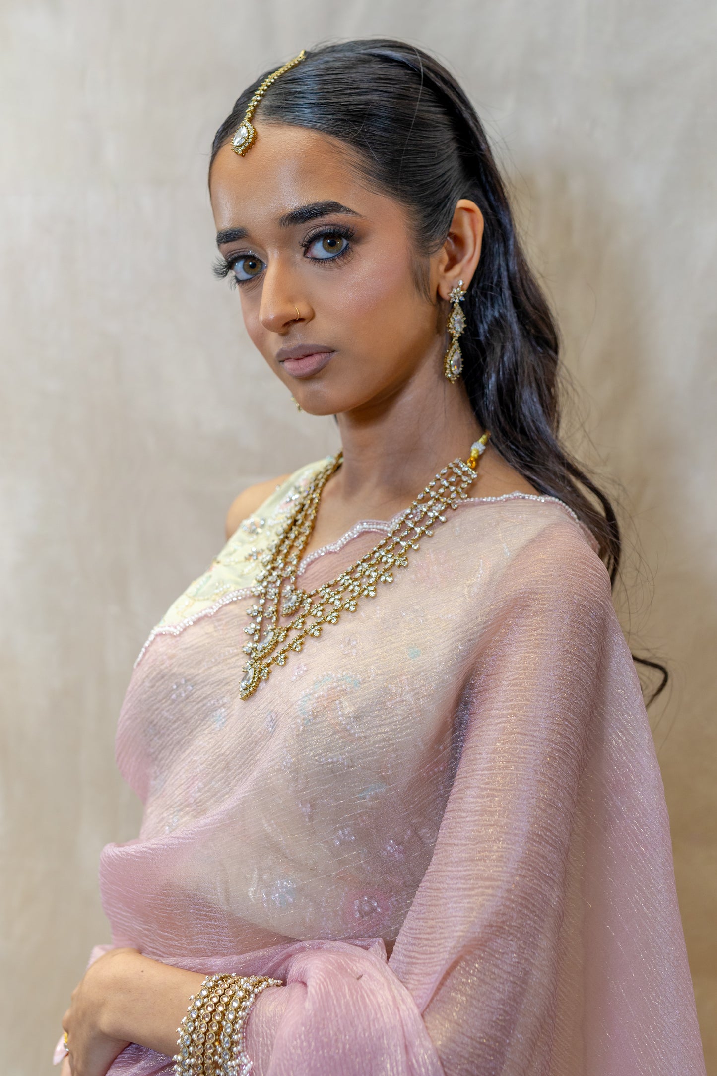Rani Three-Layered Crystal Necklace and Tikka Set styled with a light Pink Saree — Regal South Asian bridal look curated in London.