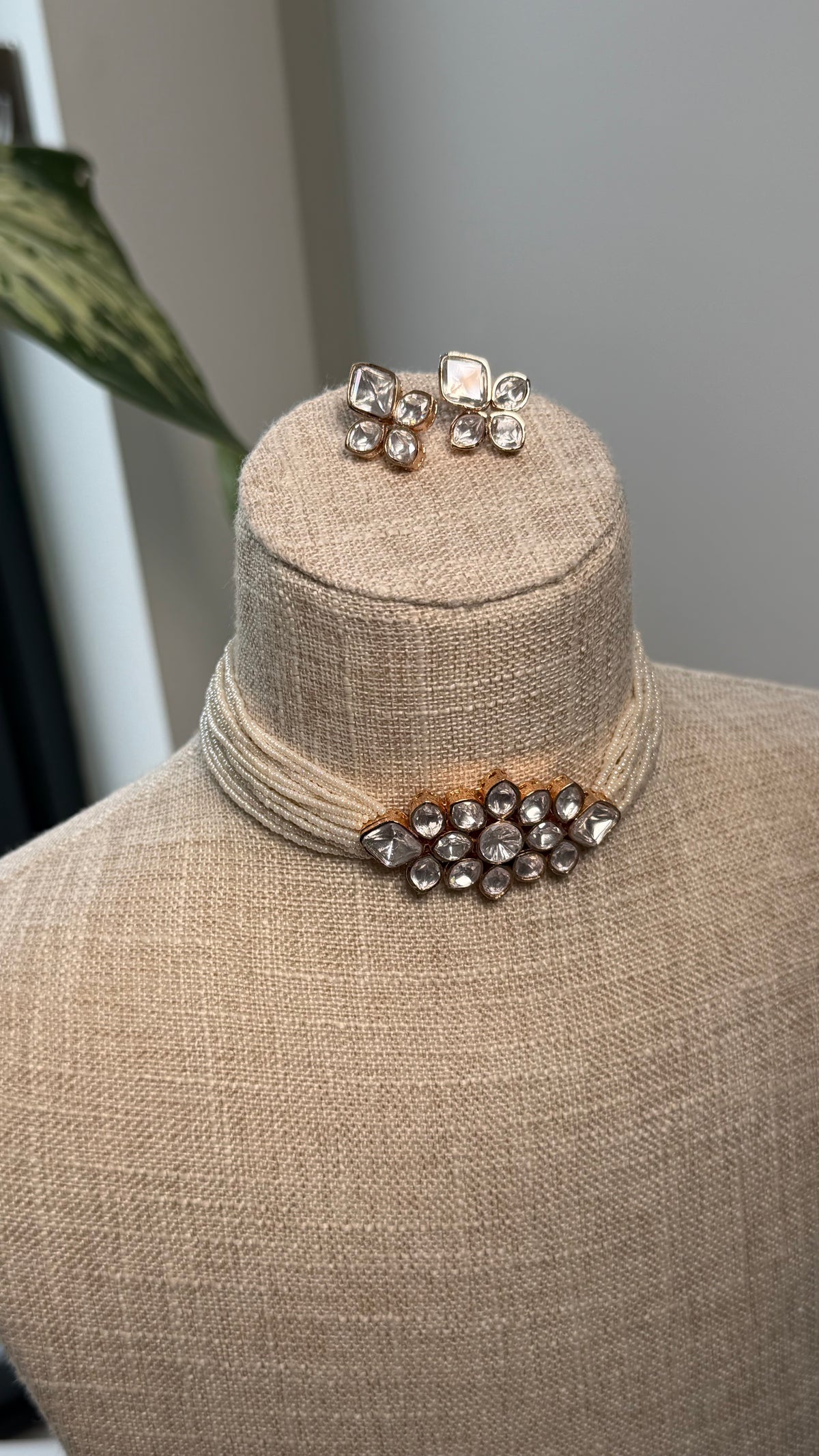 The Rhea Set by Kirosa London featuring a multi-strand cream seed bead choker with a gold Kundan cluster centerpiece and matching floral stud earrings.