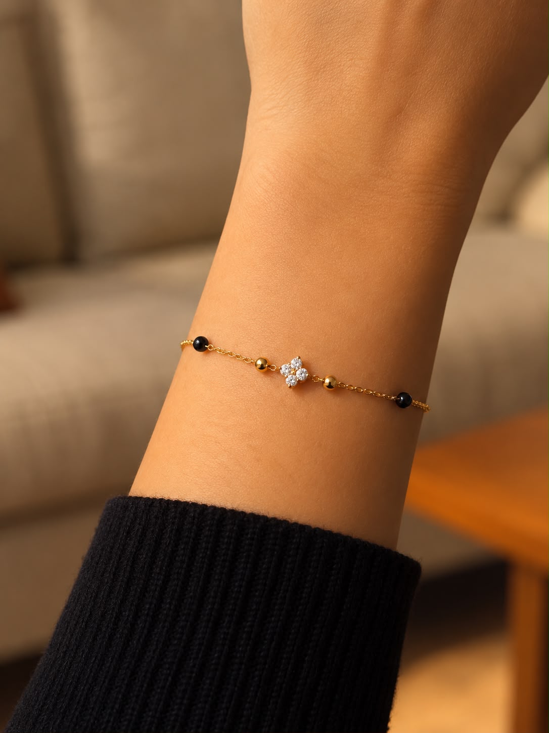 Close-up of a model wearing the Kirosa London gold Samya Mangalsutra Bracelet, featuring a four-stone floral crystal motif flanked by gold and signature black beads.