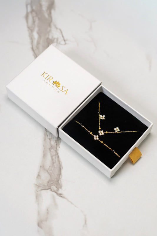The Complete Samya Gift Set by Kirosa London featuring a gold floral crystal mangalsutra necklace, matching bracelet, and stud earrings displayed in an open white gift box on a marble surface.